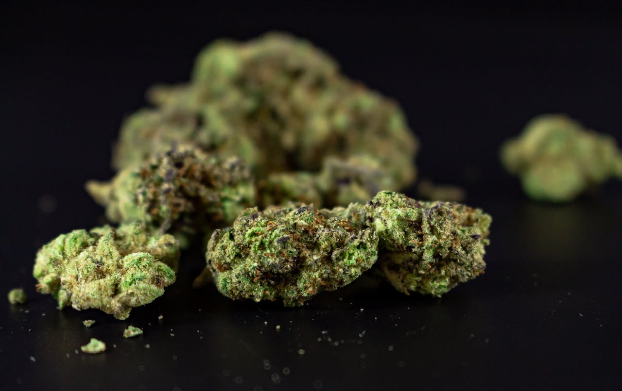 Detailed close-up of cannabis flowers, showcasing texture and color against a black backdrop.